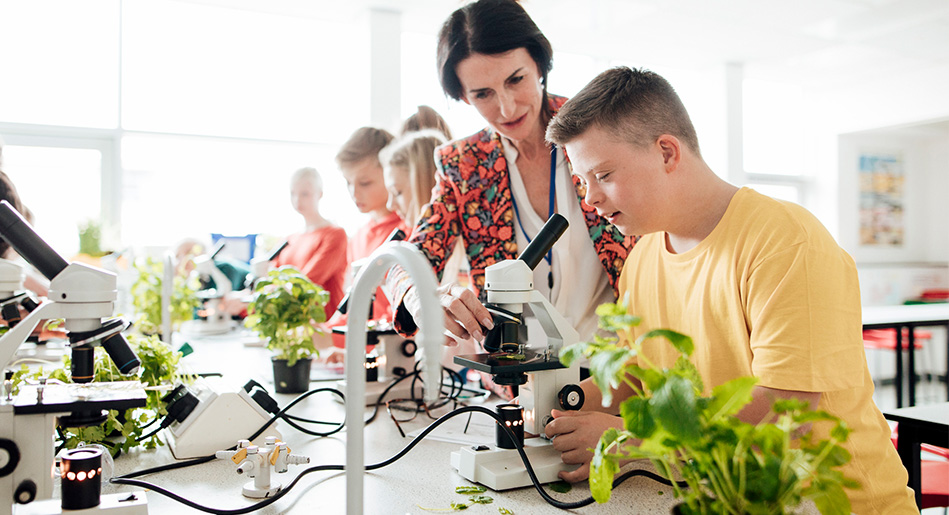 Teacher and student with Down syndrome looking in a microscope